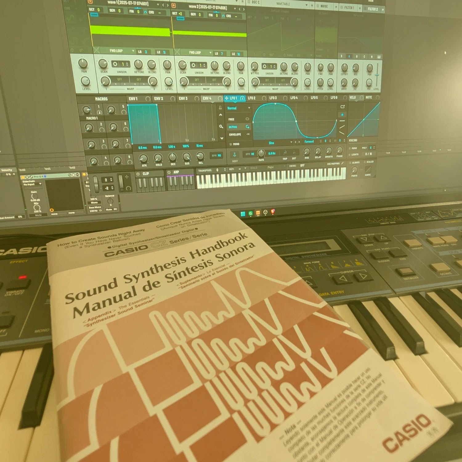 Casio sound synthesis handbook on a CZ-101 keyboard with synthesizer in the background and serum 2 running on a computer screen